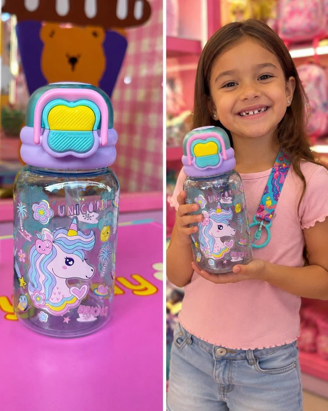 A clear unicorn water bottle with a flip lid, and a grinning girl holding the same bottle